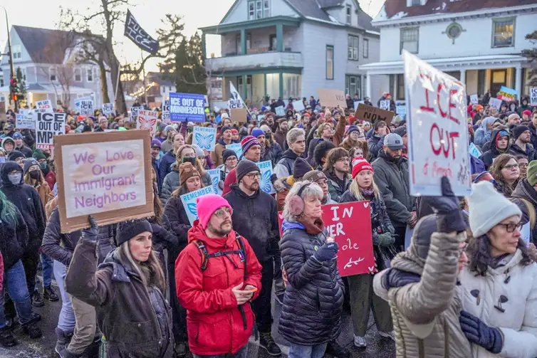 People hold signs as they gather during a vigil for a 37-year-old woman who was shot in her car by a U.S. immigration agent, according to local and federal officials, in Minneapolis, Minnesota, U.S., January 7, 2026. REUTERS/Tim Evans