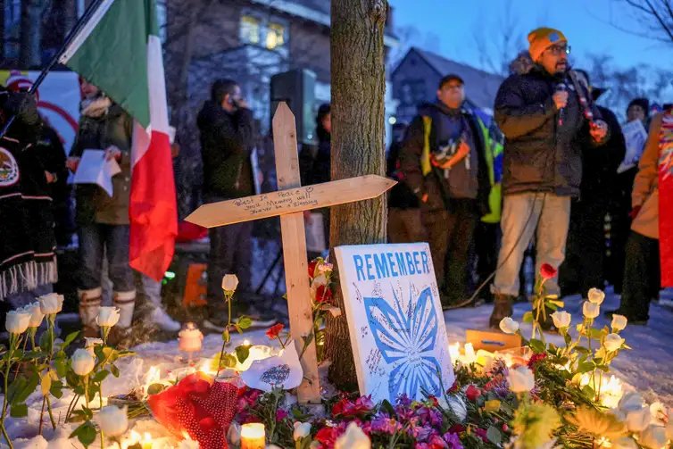 A message is written on a wooden cross placed next to flowers and candles at a memorial site during a vigil for a 37-year-old woman who was shot in her car by a U.S. immigration agent, according to local and federal officials, in Minneapolis, Minnesota, U.S., January 7, 2026. REUTERS/Tim Evans